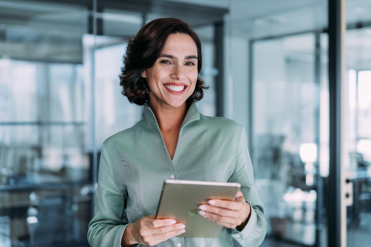 An adviser holding a tablet in a client's office, mid-conversation.